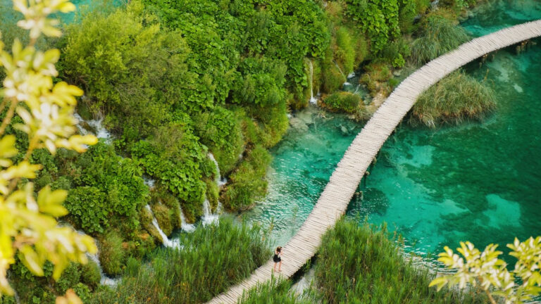 Plitvicer Seen im Mai - Holzsteg über grünlich schimmerndem Wasser im Nationalpark Plitvice in Kroatien.