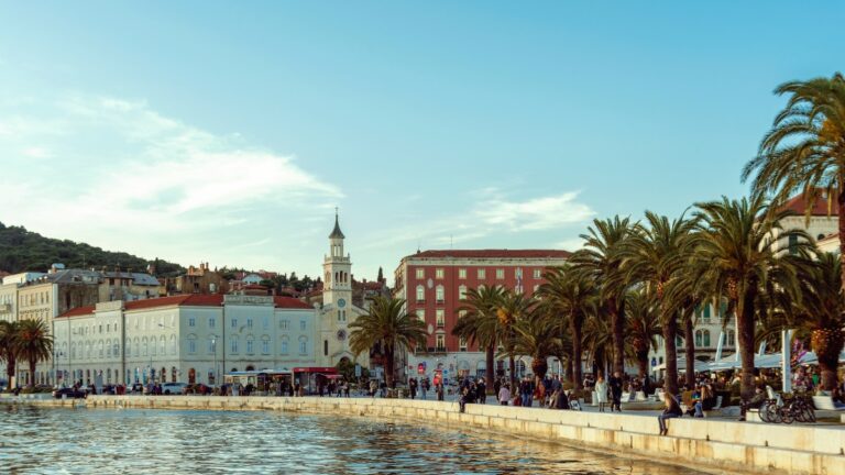 Menschen auf der Riva in Split, Kroatien, die entlang der Uferpromenade am Meer spazieren.