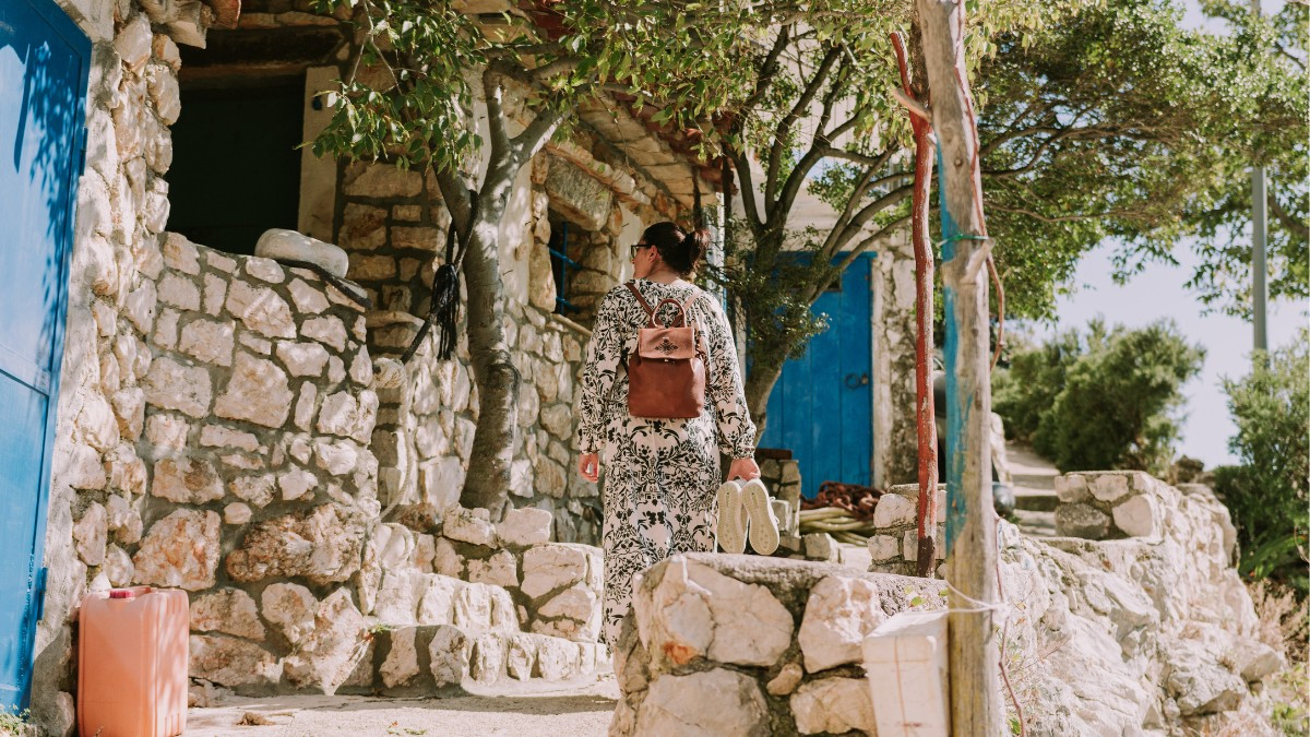 Eine Person geht in Kroatien durch eine steinerne Gasse an einem alten Steinhaus vorbei.