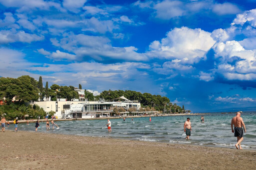 Menschen am Strand von Bačvice in Split, Kroatien, die im flachen Wasser stehen und baden.
