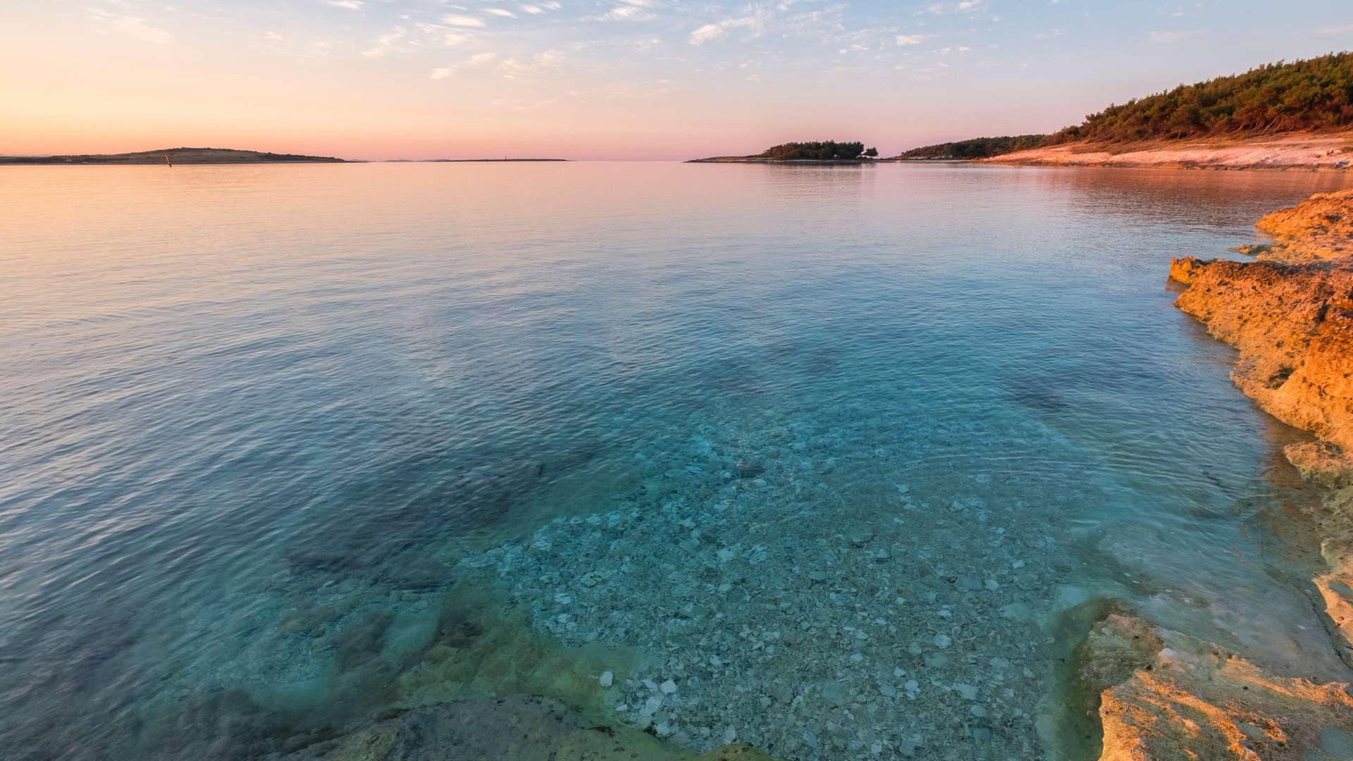 Ruhige Küstenlinie an der Adria in Istrien, Kamenjak Kroatien, im warmen Abendlicht, klares Wasser und felsiger Uferbereich.