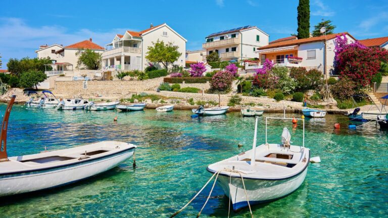 Küstenort in Kroatien im Juli mit klarem türkisblauem Meer, kleinen Booten und Häusern am Wasser