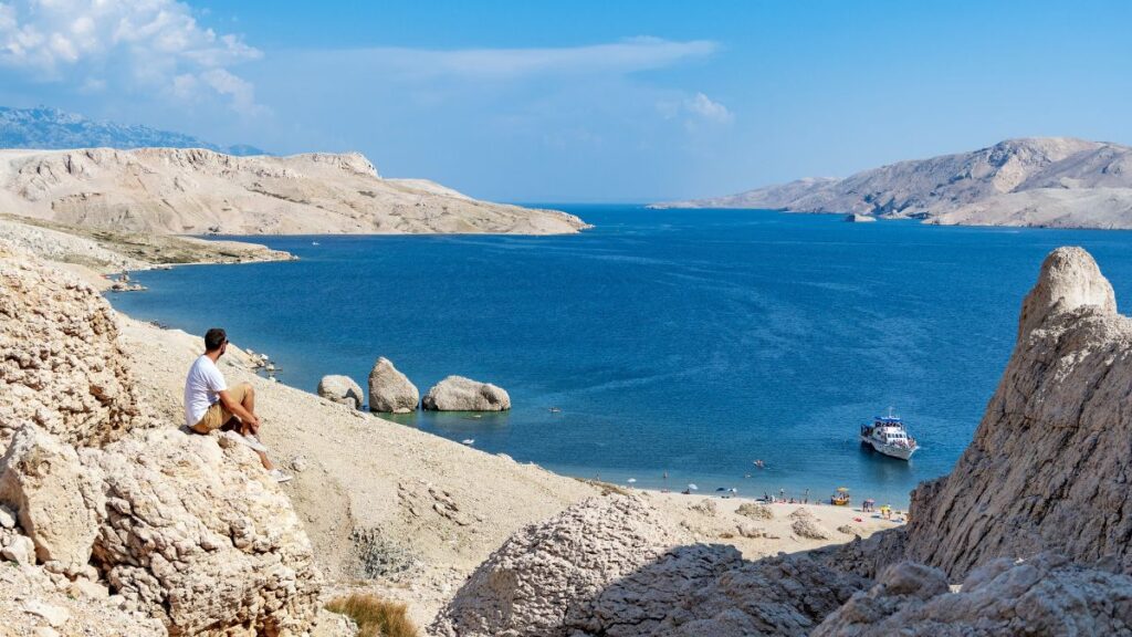 Karge Landschaft der Insel Pag mit hellem Stein, blauem Meer und Blick auf eine Bucht in Kroatien