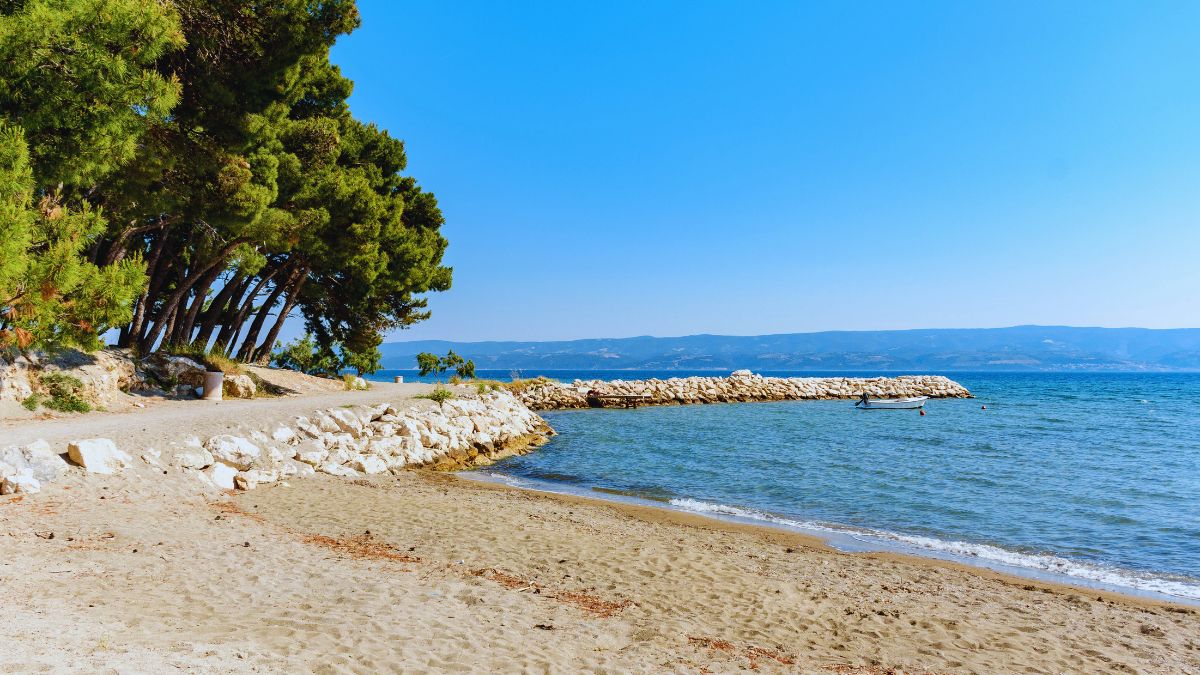 Sandstrand von Duće bei Omiš mit Pinien und flachem Meer